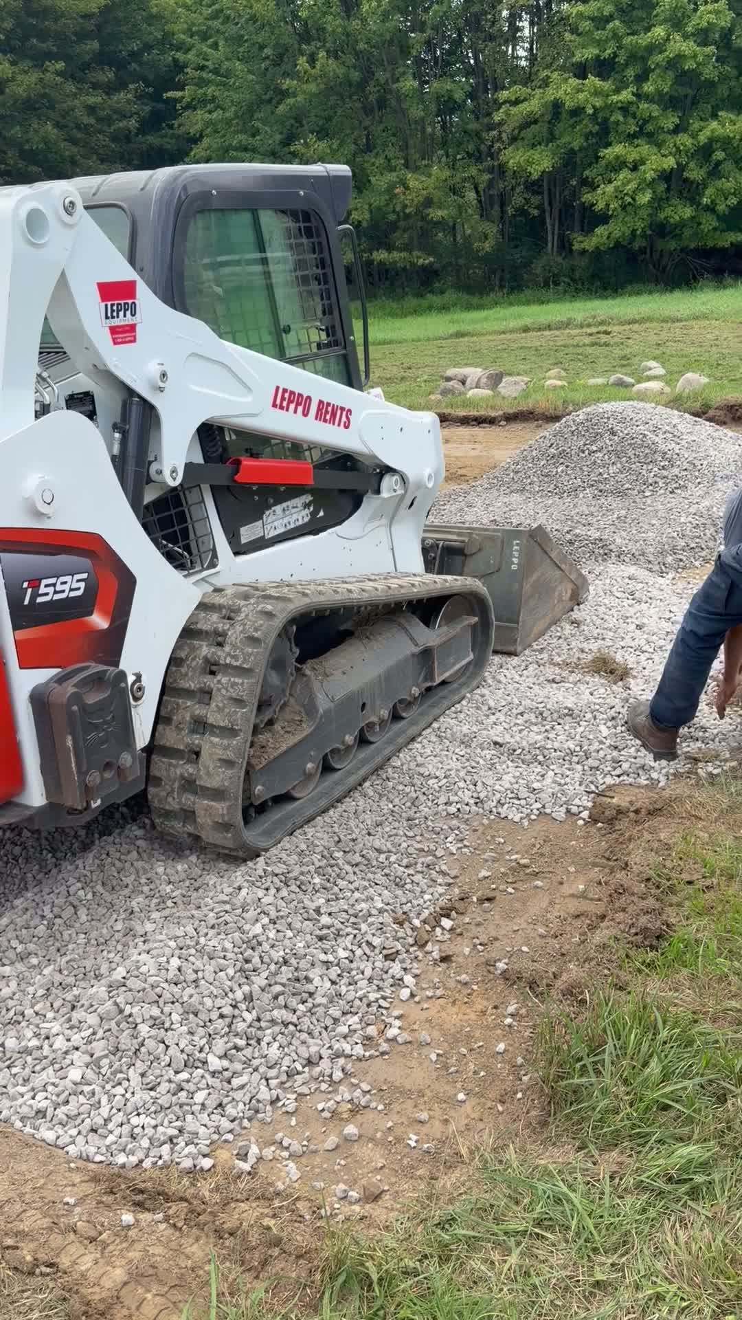 The crew and a tracked loader preparing a gravel base for a stonework project.