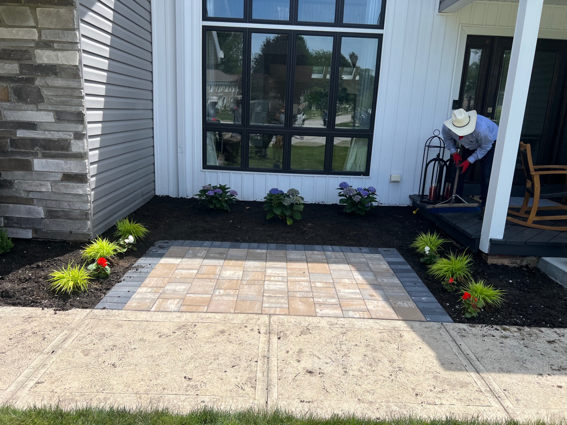 A paver walkway in a herringbone blend with a charcoal soldier border, framed by fresh mulch and hydrangeas.