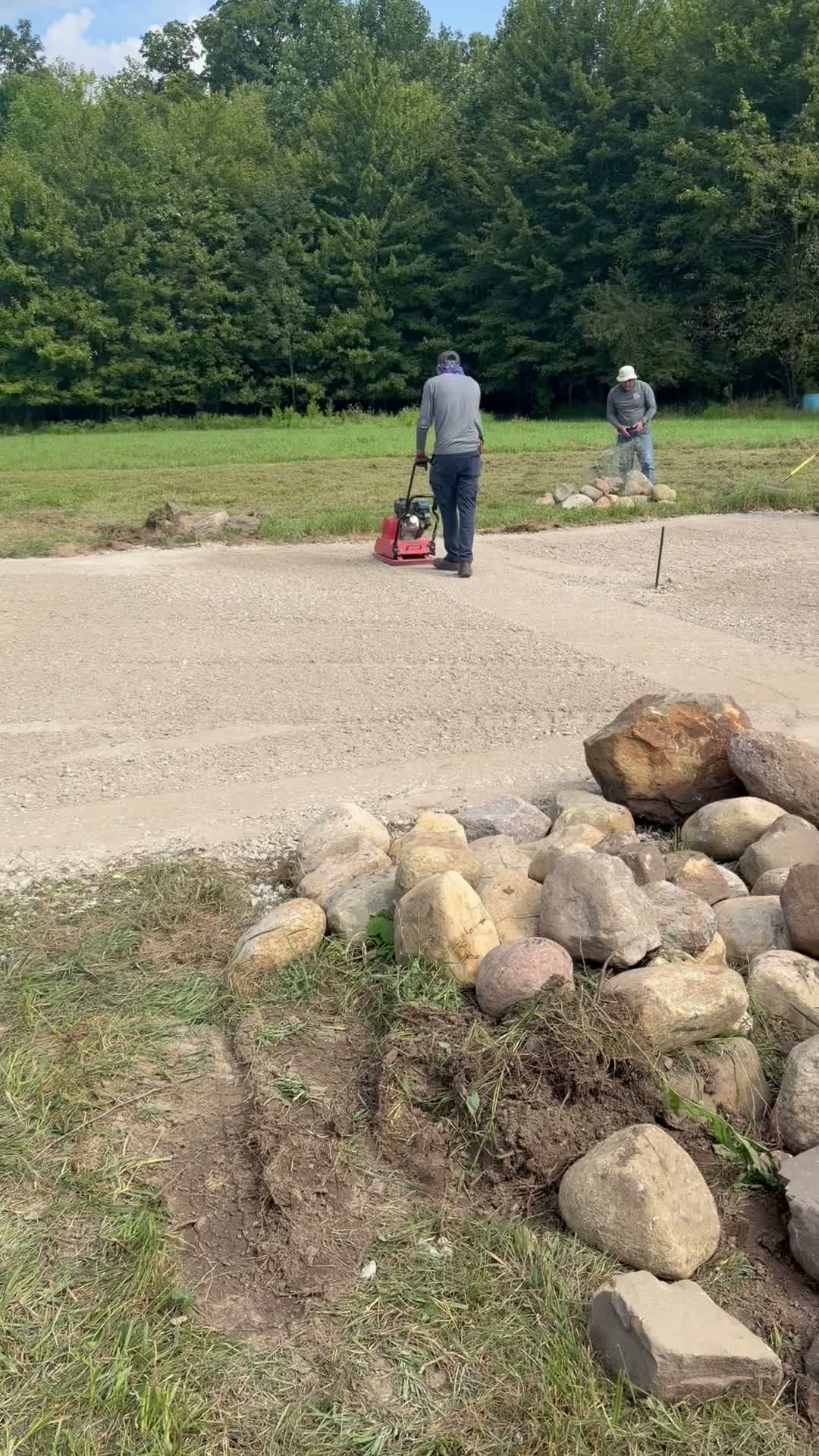 An on-site video of the crew compacting a patio base beside natural boulders.