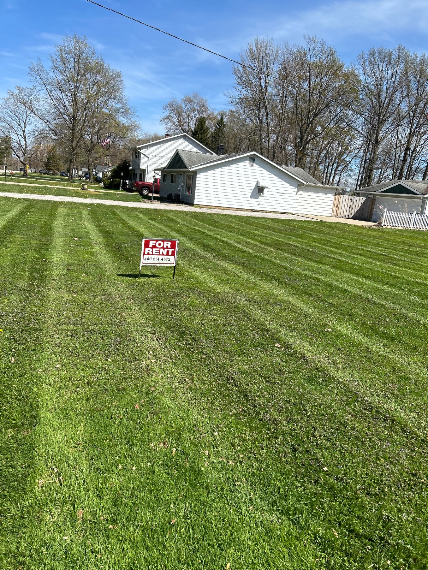 Fresh mowing stripes across a wide front lawn, edged clean to the sidewalk and drive.